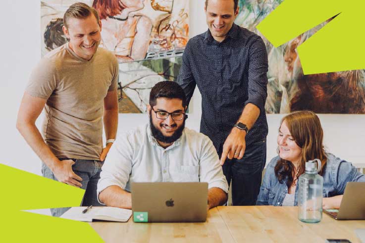 A group of social media management people gathered around a computer